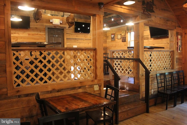 wine area featuring vaulted ceiling, hardwood / wood-style floors, and wood walls