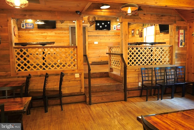 staircase with wood ceiling, hardwood / wood-style flooring, wood walls, and vaulted ceiling with beams