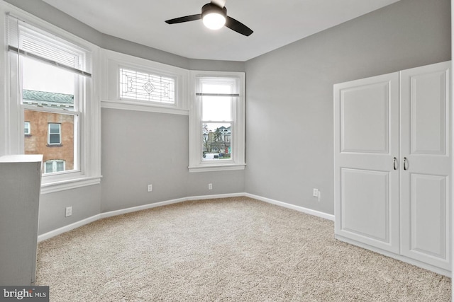 unfurnished bedroom with ceiling fan, light colored carpet, and multiple windows