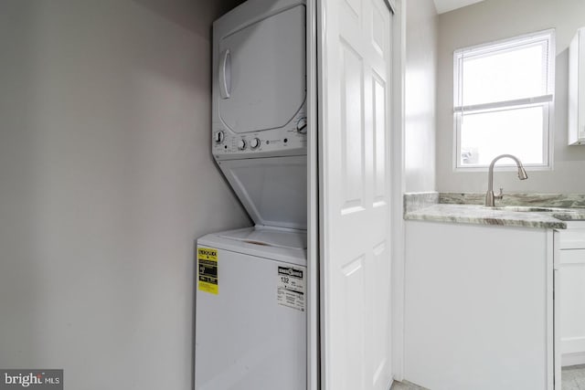 clothes washing area with stacked washing maching and dryer and sink