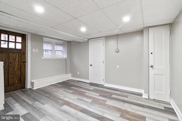 basement featuring light wood-type flooring and a drop ceiling