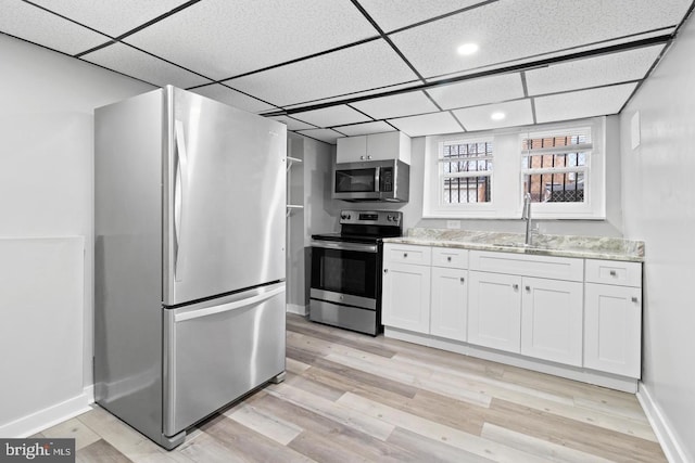 kitchen featuring sink, white cabinets, light hardwood / wood-style flooring, stainless steel appliances, and a drop ceiling