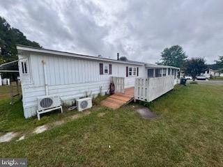 back of property featuring ac unit, a deck, and a lawn