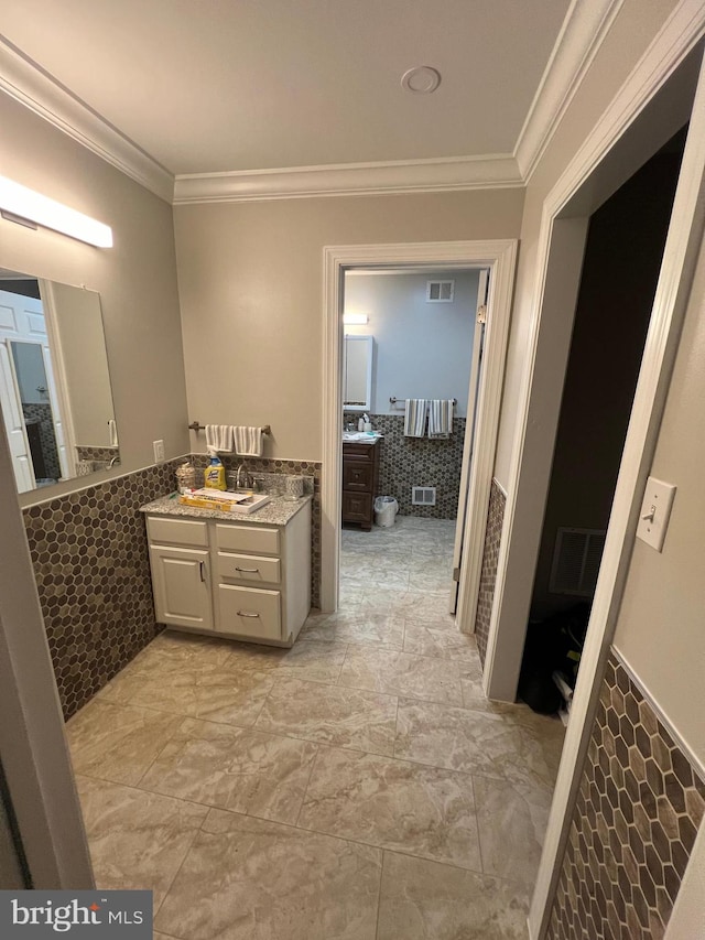 bathroom with crown molding, tile walls, and vanity