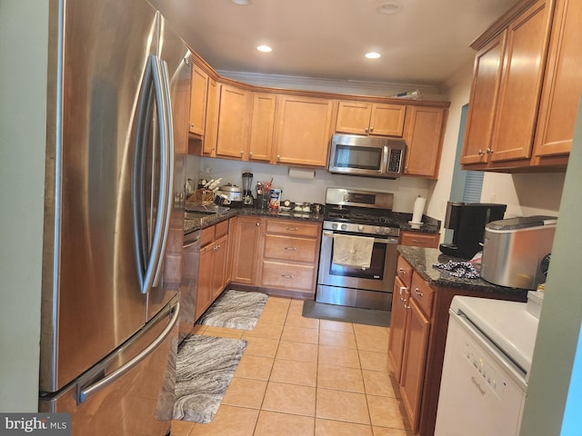 kitchen featuring appliances with stainless steel finishes, crown molding, dark stone countertops, and light tile patterned floors