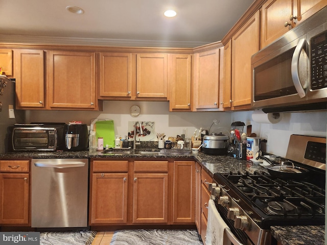 kitchen with dark stone countertops, light tile patterned floors, appliances with stainless steel finishes, and sink