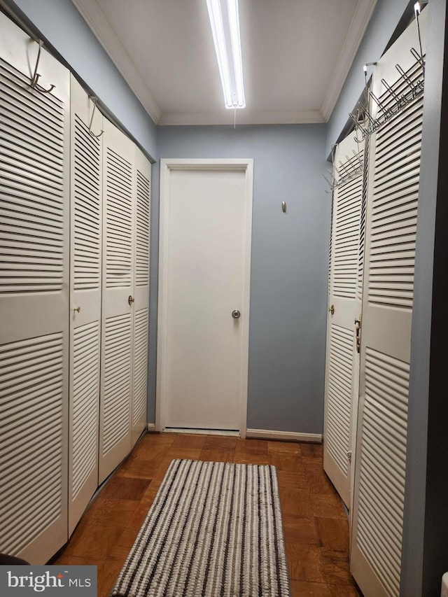 entryway with ornamental molding and dark parquet flooring