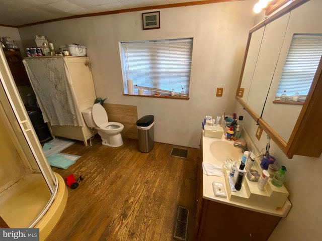 bathroom featuring vanity, hardwood / wood-style flooring, a shower with door, ornamental molding, and toilet