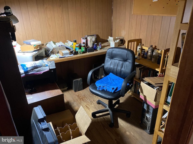 office featuring wooden walls, built in desk, and wood-type flooring