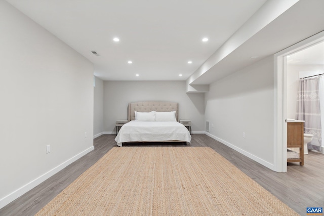 bedroom with ensuite bathroom and hardwood / wood-style flooring