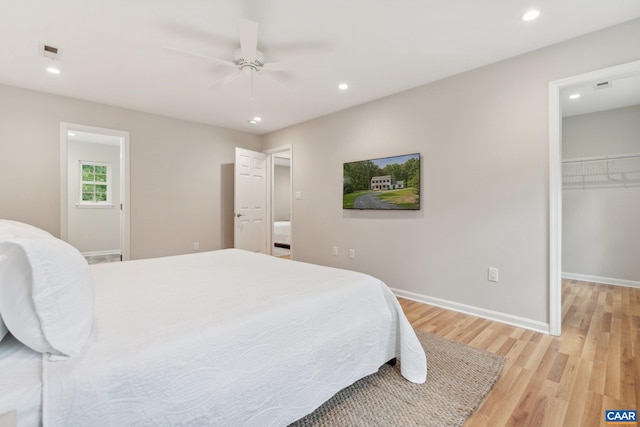 bedroom with a closet, ceiling fan, a spacious closet, and light hardwood / wood-style flooring