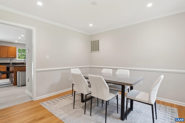 dining room featuring light wood-type flooring and ornamental molding