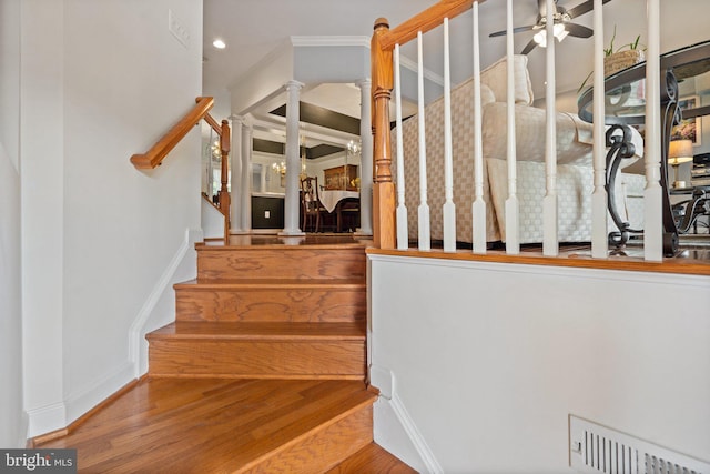 stairway with ceiling fan, crown molding, and wood-type flooring