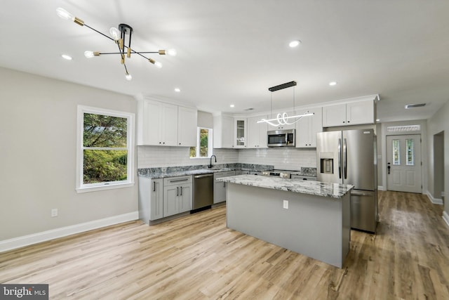 kitchen with pendant lighting, sink, a kitchen island, white cabinetry, and appliances with stainless steel finishes