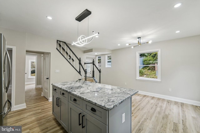 kitchen with light wood-type flooring, a notable chandelier, decorative light fixtures, and a center island