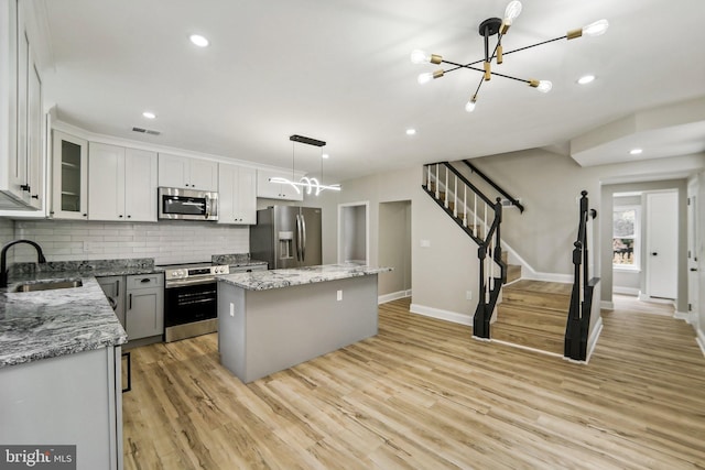 kitchen with sink, white cabinetry, stainless steel appliances, a center island, and light hardwood / wood-style floors