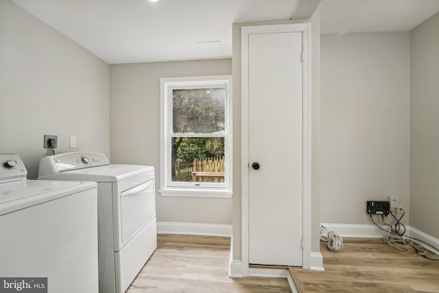 laundry area with light hardwood / wood-style floors and washer and dryer