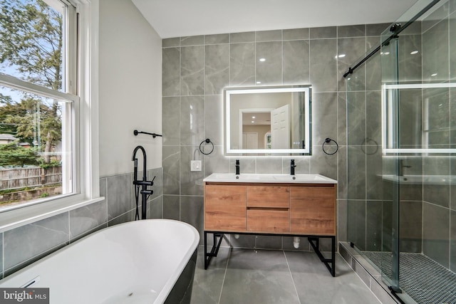 bathroom featuring independent shower and bath, vanity, and tile walls