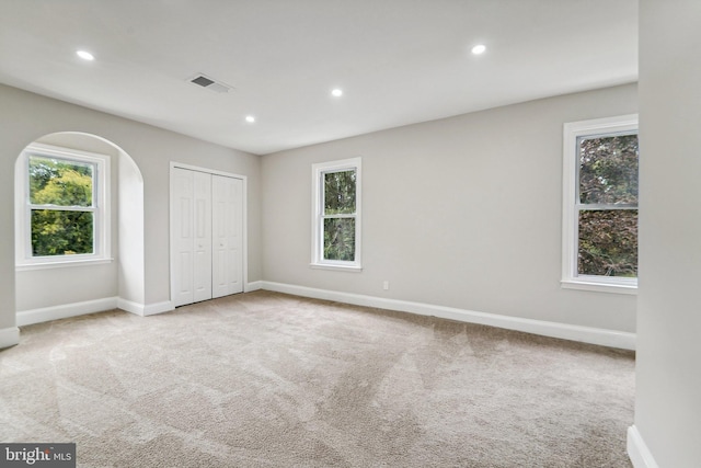 unfurnished bedroom with multiple windows, a closet, and light colored carpet