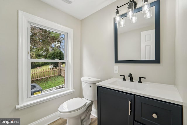 bathroom with wood-type flooring, a healthy amount of sunlight, vanity, and toilet