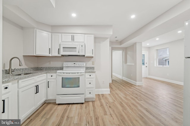 kitchen with white appliances, white cabinets, light stone counters, and light wood-type flooring