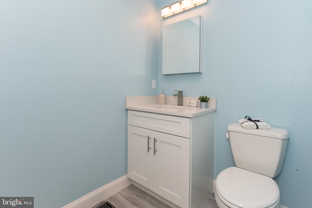 bathroom with vanity, toilet, and wood-type flooring