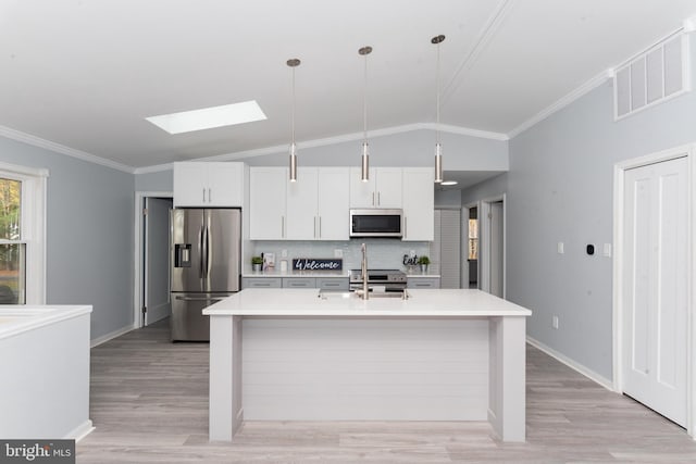 kitchen with white cabinets, appliances with stainless steel finishes, lofted ceiling with skylight, and pendant lighting