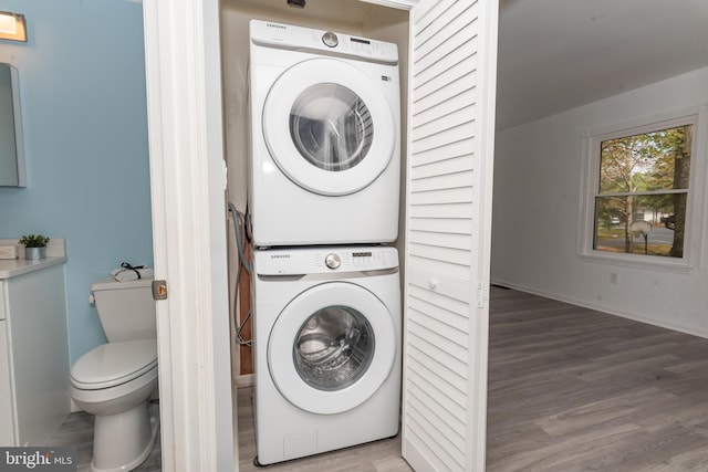 clothes washing area with stacked washer / dryer and wood-type flooring