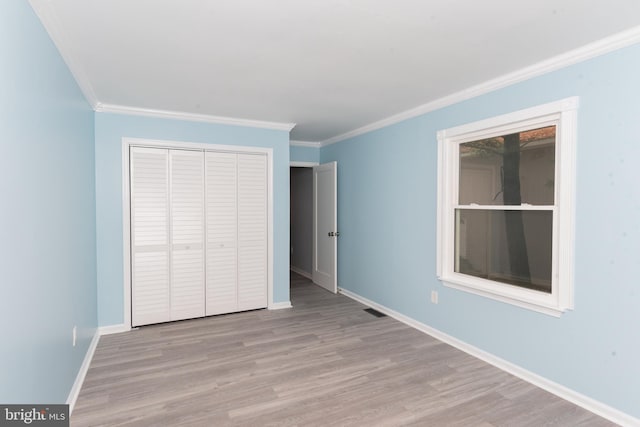 unfurnished bedroom with a closet, ornamental molding, and light hardwood / wood-style flooring