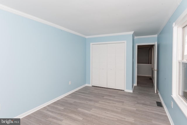 unfurnished bedroom featuring crown molding, light hardwood / wood-style flooring, and a closet