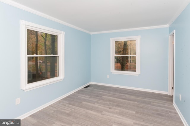 empty room with ornamental molding and light hardwood / wood-style flooring