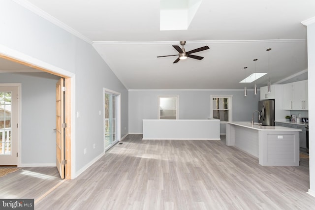 kitchen with a kitchen island with sink, stainless steel fridge, lofted ceiling, and hanging light fixtures