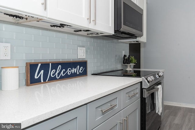 kitchen with gray cabinets, appliances with stainless steel finishes, hardwood / wood-style floors, and decorative backsplash