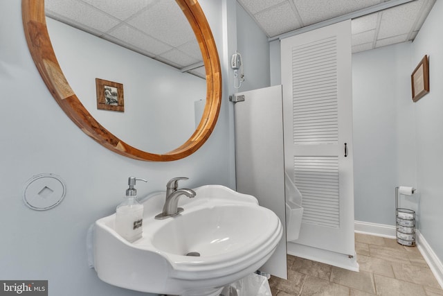 bathroom featuring a paneled ceiling and sink