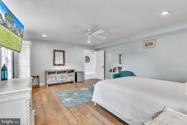 bedroom with light hardwood / wood-style flooring, ceiling fan, and stainless steel fridge