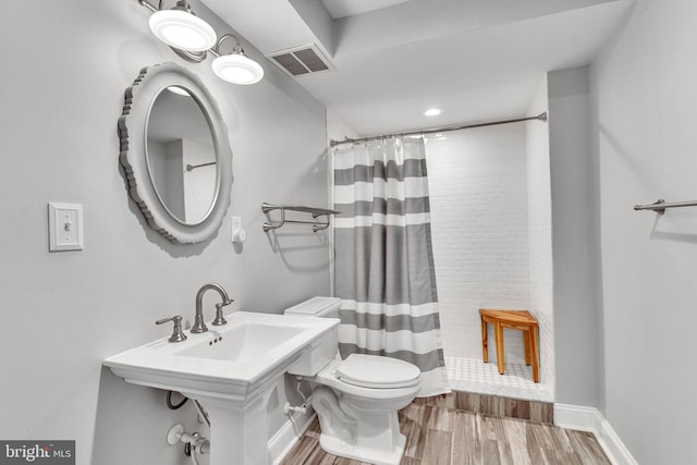 bathroom with a shower with shower curtain, hardwood / wood-style floors, and toilet