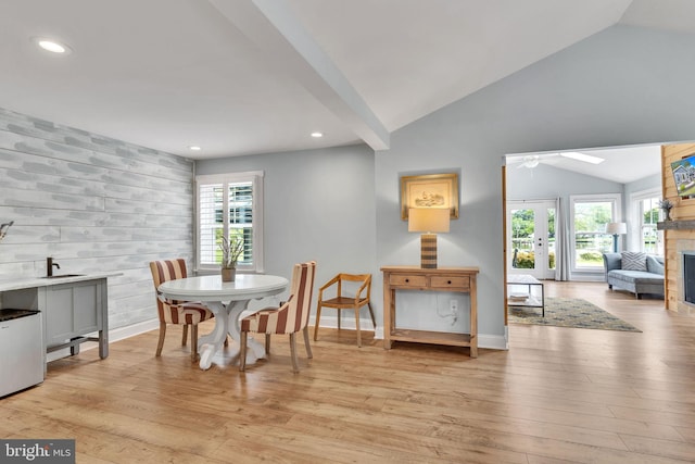 dining area with a healthy amount of sunlight, light hardwood / wood-style floors, and vaulted ceiling