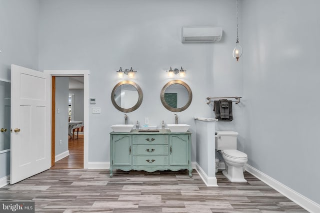 bathroom featuring wood-type flooring, vanity, toilet, and a wall mounted AC