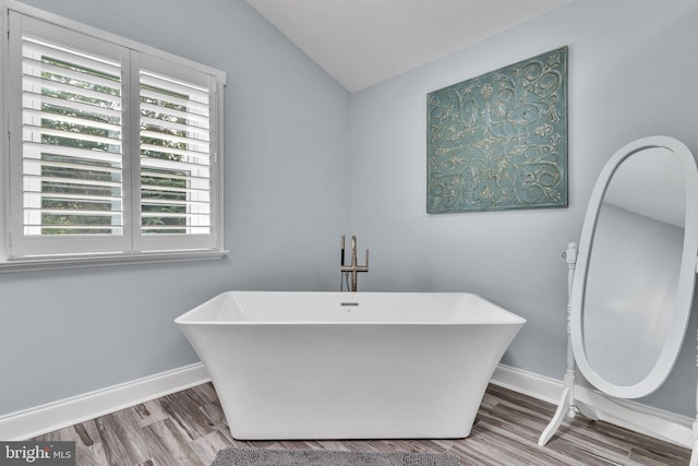 bathroom featuring wood-type flooring, lofted ceiling, and a washtub