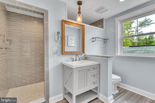 bathroom featuring tiled shower, vanity, toilet, and hardwood / wood-style flooring