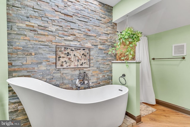 bathroom featuring wood-type flooring and a tub to relax in