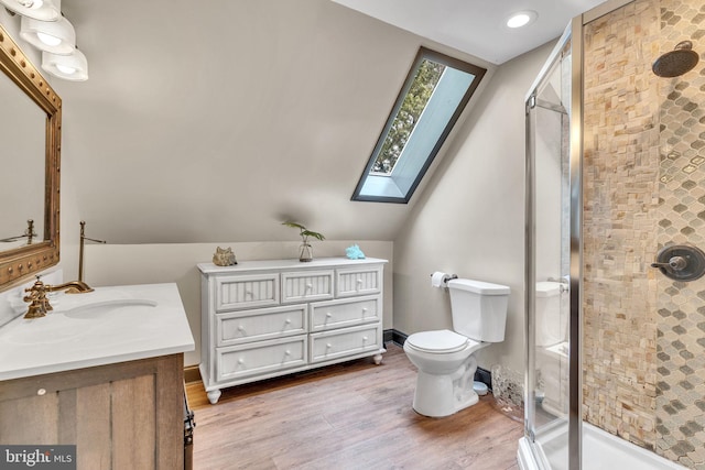 bathroom with vanity, wood-type flooring, a shower with shower door, lofted ceiling with skylight, and toilet