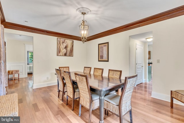 dining room with crown molding, light hardwood / wood-style floors, and a chandelier