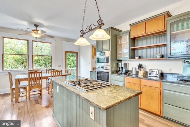 kitchen featuring pendant lighting, light hardwood / wood-style floors, a kitchen island, appliances with stainless steel finishes, and ceiling fan