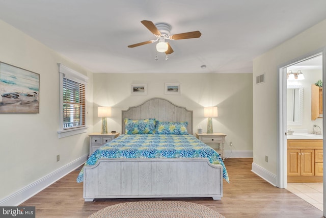 bedroom with light hardwood / wood-style flooring, ceiling fan, ensuite bathroom, and sink