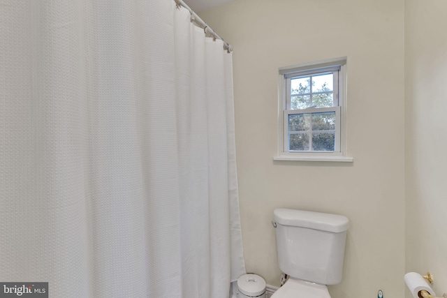 bathroom featuring toilet and curtained shower