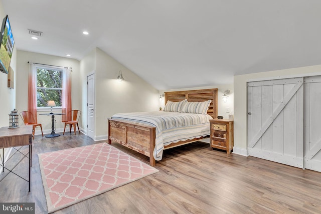 bedroom featuring hardwood / wood-style floors and a barn door