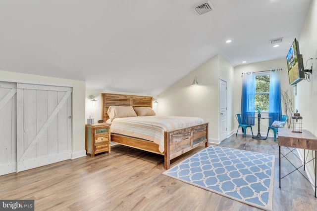 bedroom with light wood-type flooring and a barn door