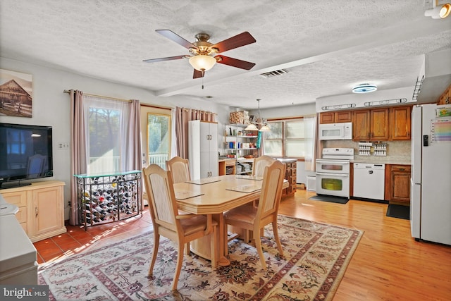 dining area with ceiling fan, light hardwood / wood-style flooring, and a textured ceiling