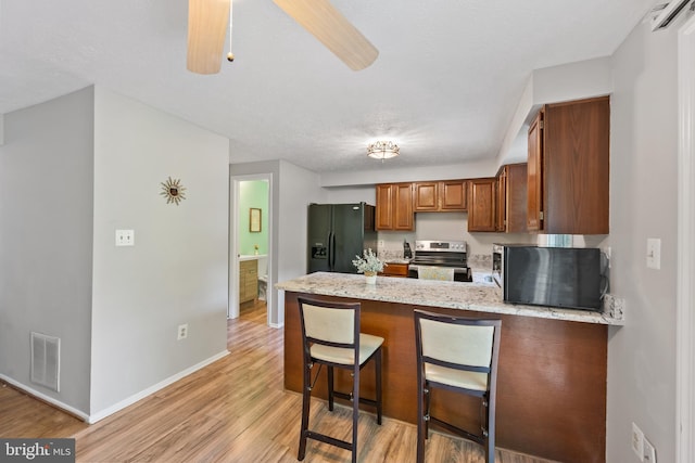 kitchen with ceiling fan, light wood-type flooring, black refrigerator with ice dispenser, light stone countertops, and stainless steel electric range oven